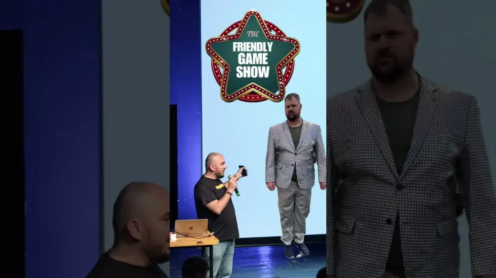 Hosts on stage under the Friendly Game Show sign